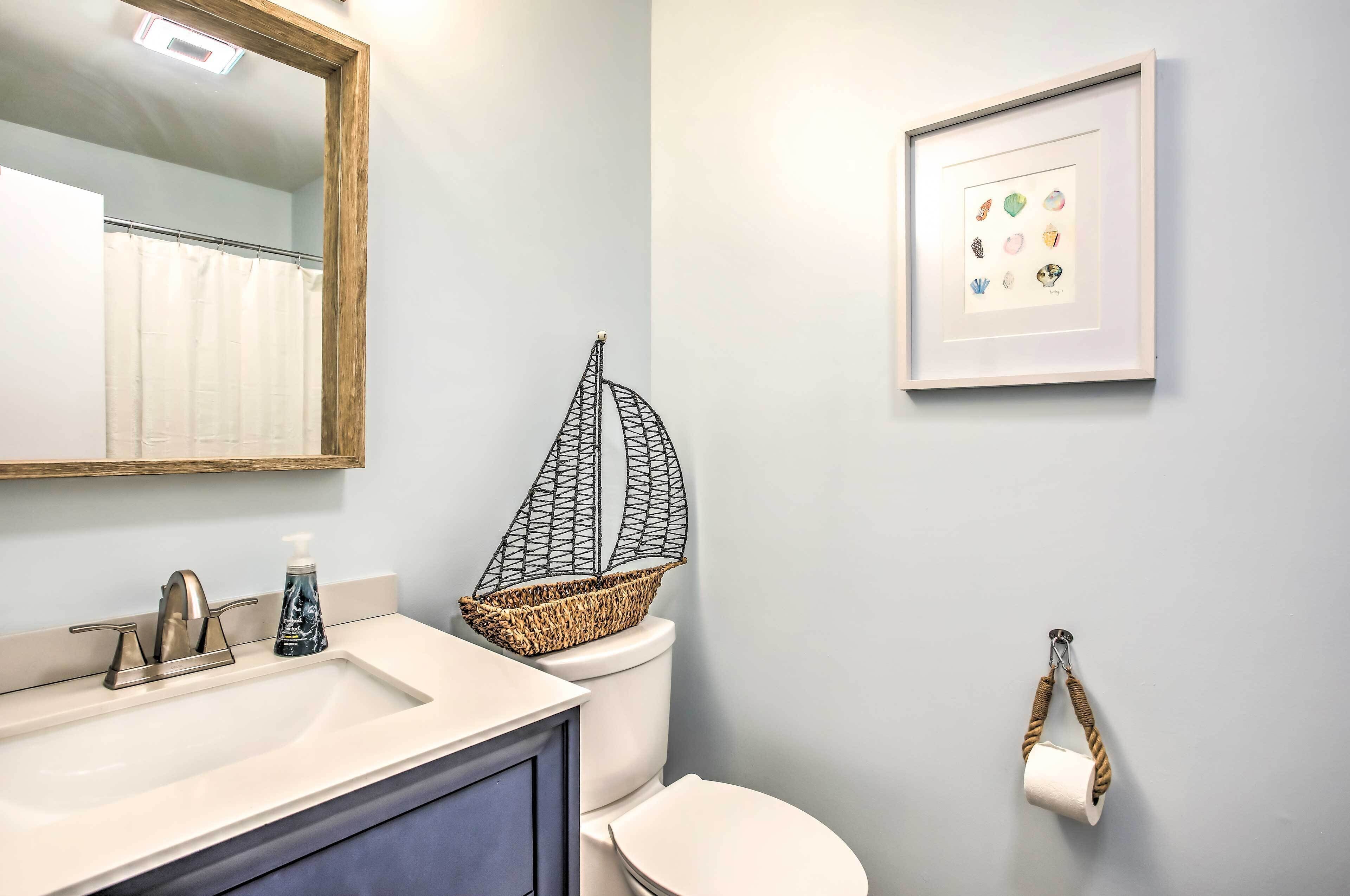 A bathroom with a sink, toilet, and a framed picture on the wall.