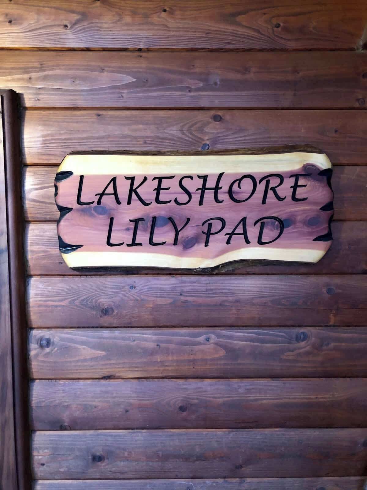 A wooden sign with the text "LAKESHORE LILY PAD" on a wooden wall.