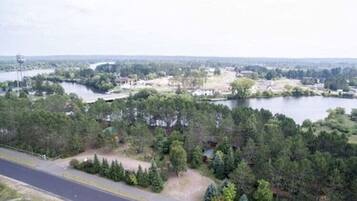 Une vue sur un lac, avec une route, des arbres et des bâtiments visibles au loin.