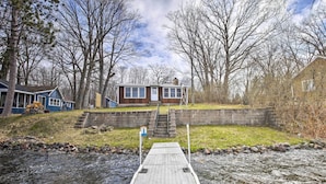 A wooden dock leading to a house with a stone staircase and a small building with windows. - Lakefront 1930’s Log Cabin w/ Dock & Fire Pit! (Rice Lake)