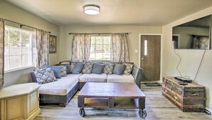 A living room with a sectional sofa, a wooden coffee table, a vintage suitcase, and a television mounted on the wall. - Kingston Sleeper: Unique Stay Near Silver Mountain (Kingston)