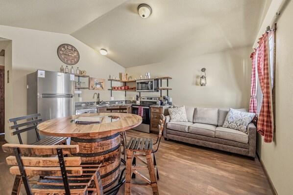 A compact kitchen with a central island, a refrigerator, microwave, and a dining area with wooden chairs.