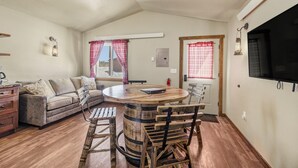 A cozy room with a wooden dining table, a sofa, and a TV. - Family-Friendly Old West Cabin Near YNP (Island Park)