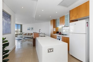 Une cuisine moderne avec des meubles blancs, un îlot central et un four encastré.