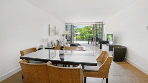 A modern dining area with a glass table, wicker chairs, and a view of the outdoors.