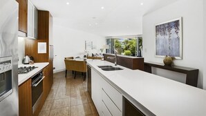 A modern kitchen with a large island, built-in oven, and a dining area with a wooden table and chairs.