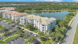 Un edificio residencial de varios pisos con un patio central y un lago al fondo.
