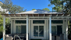 Een overdekt buitengebied met een zwembad, zitplaatsen en een pergola.