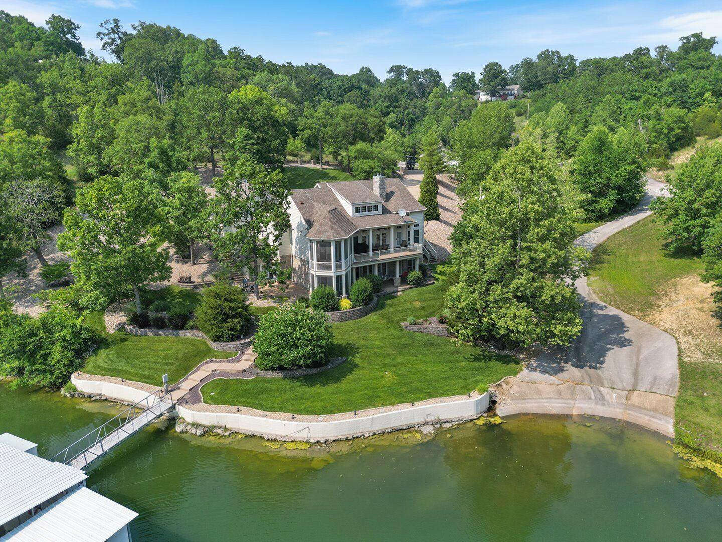 A large house with a two-story porch, a dock, and a pond.