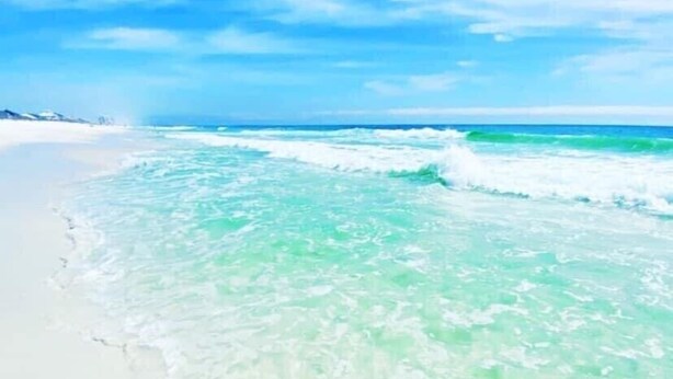 Une plage à l’eau turquoise et limpide et au sable blanc.