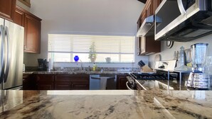 A kitchen with a granite countertop, stainless steel appliances, and wooden cabinets.