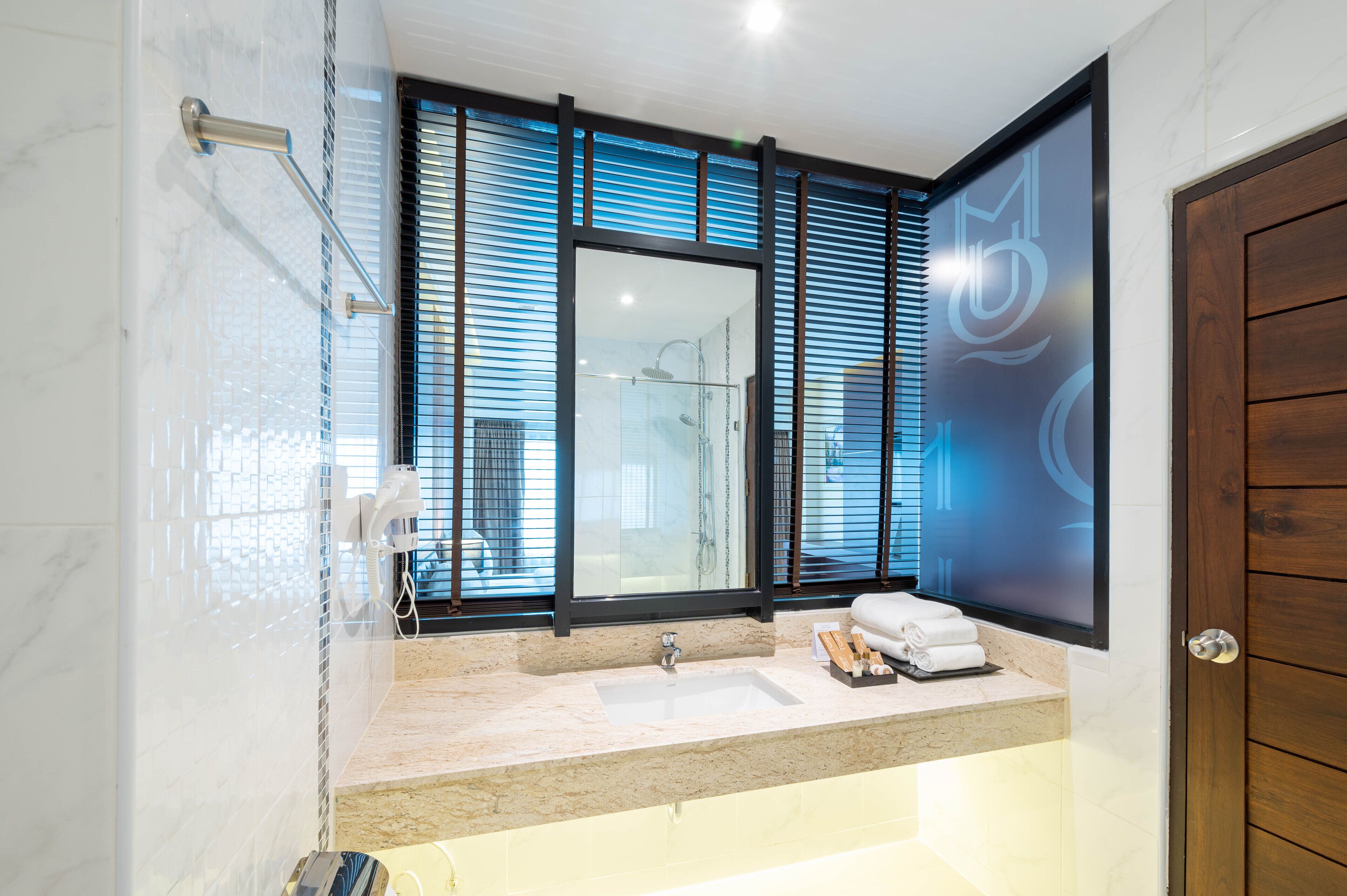 Un baño moderno con un espejo grande, un lavabo y una zona de ducha.