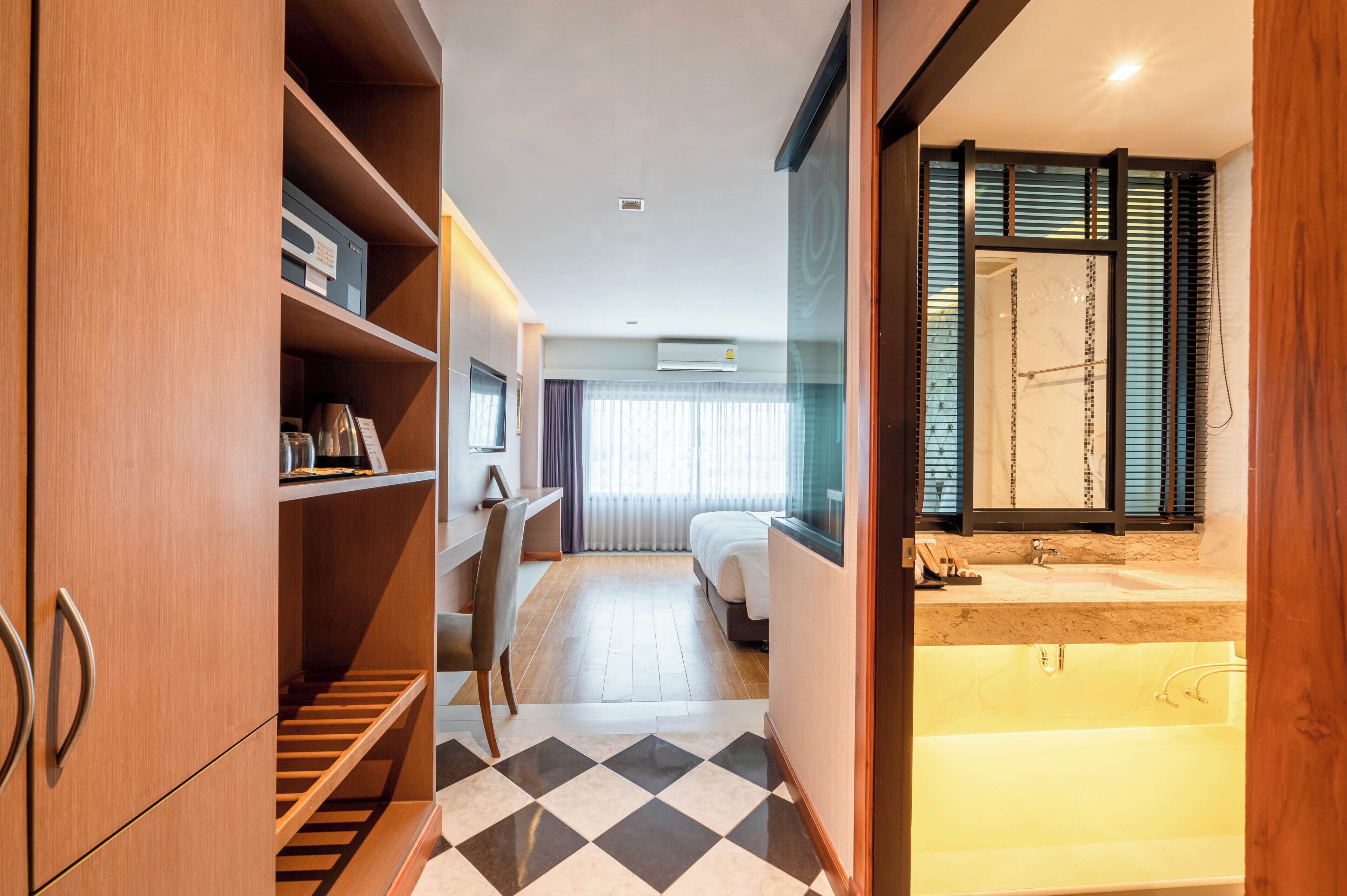 Habitación de hotel con piso a cuadros, una cama, un escritorio y un baño con bañera y ducha.