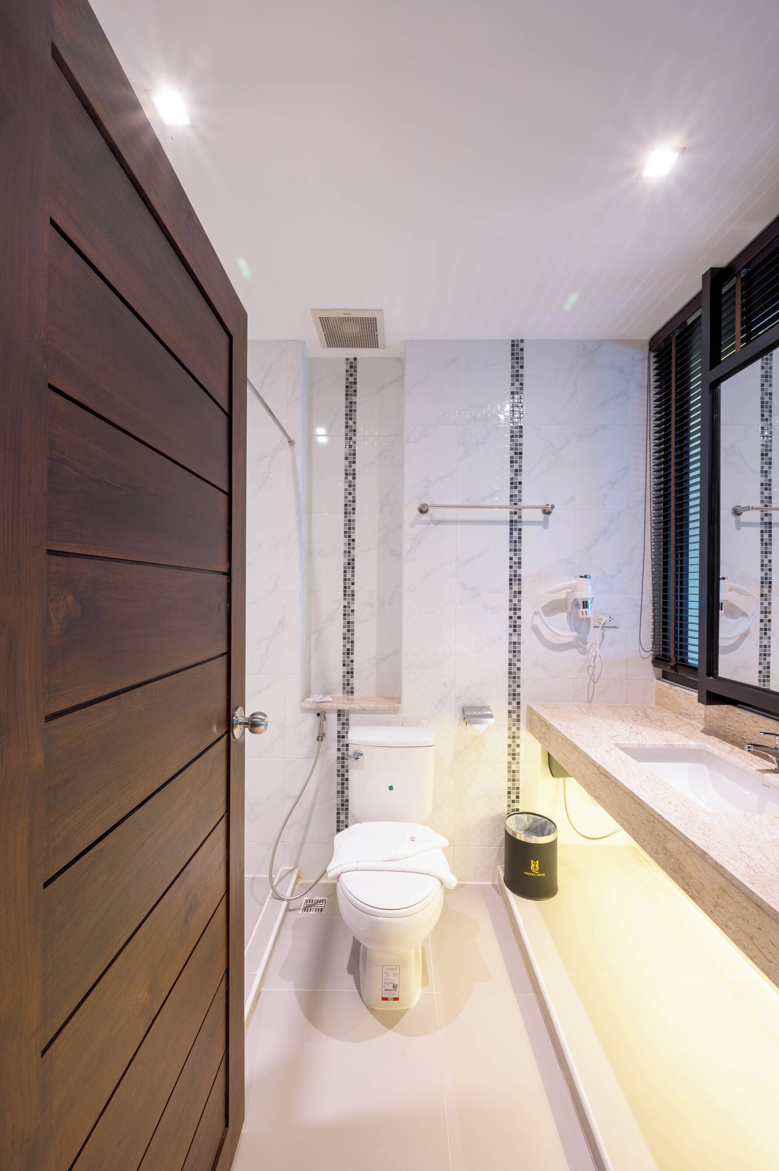 Une salle de bain moderne avec une porte en bois, des toilettes, un espace douche et un meuble-lavabo avec un miroir.