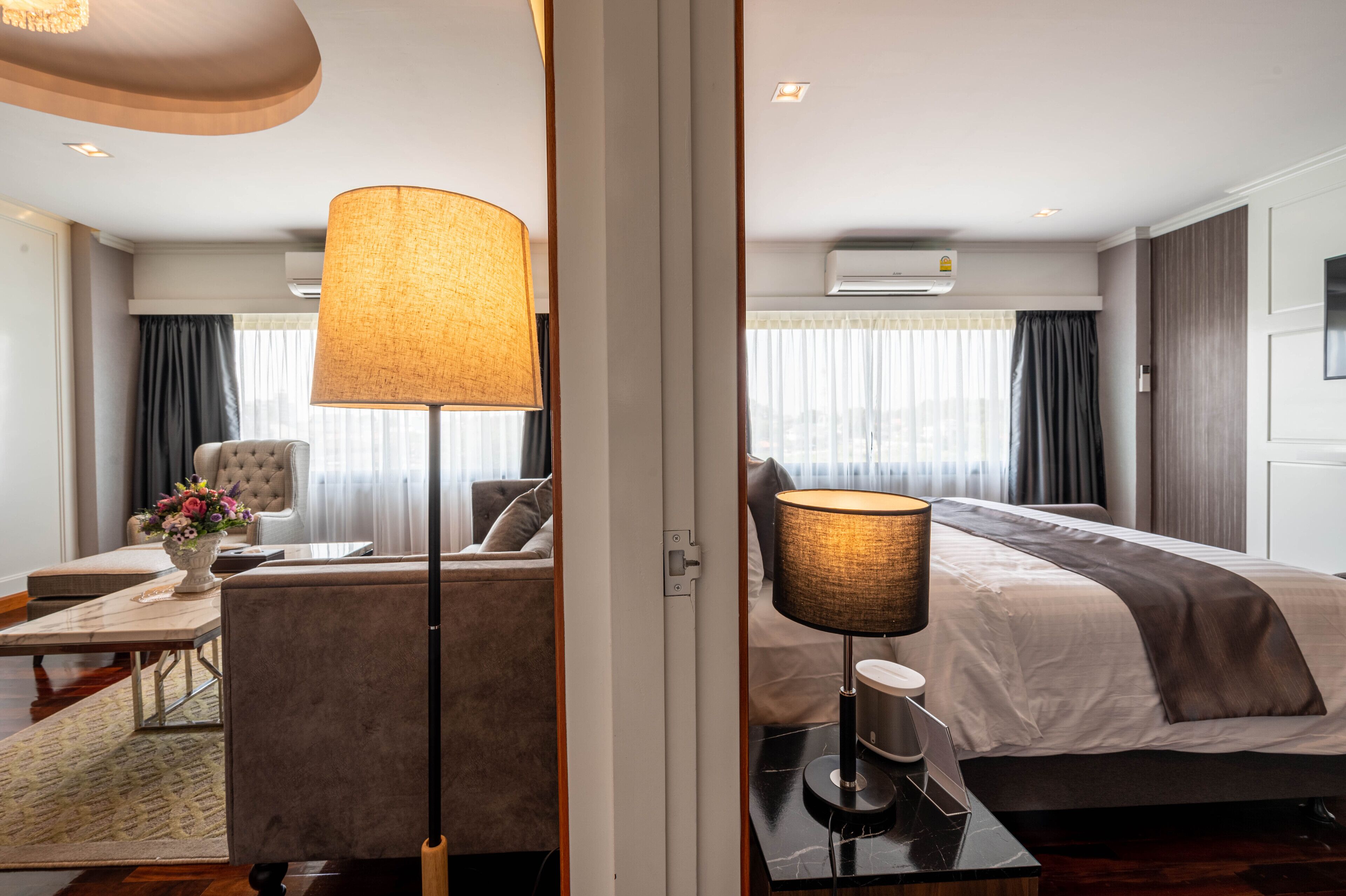 A hotel room with a bed, a desk, a chair, a lamp, and a window with curtains.