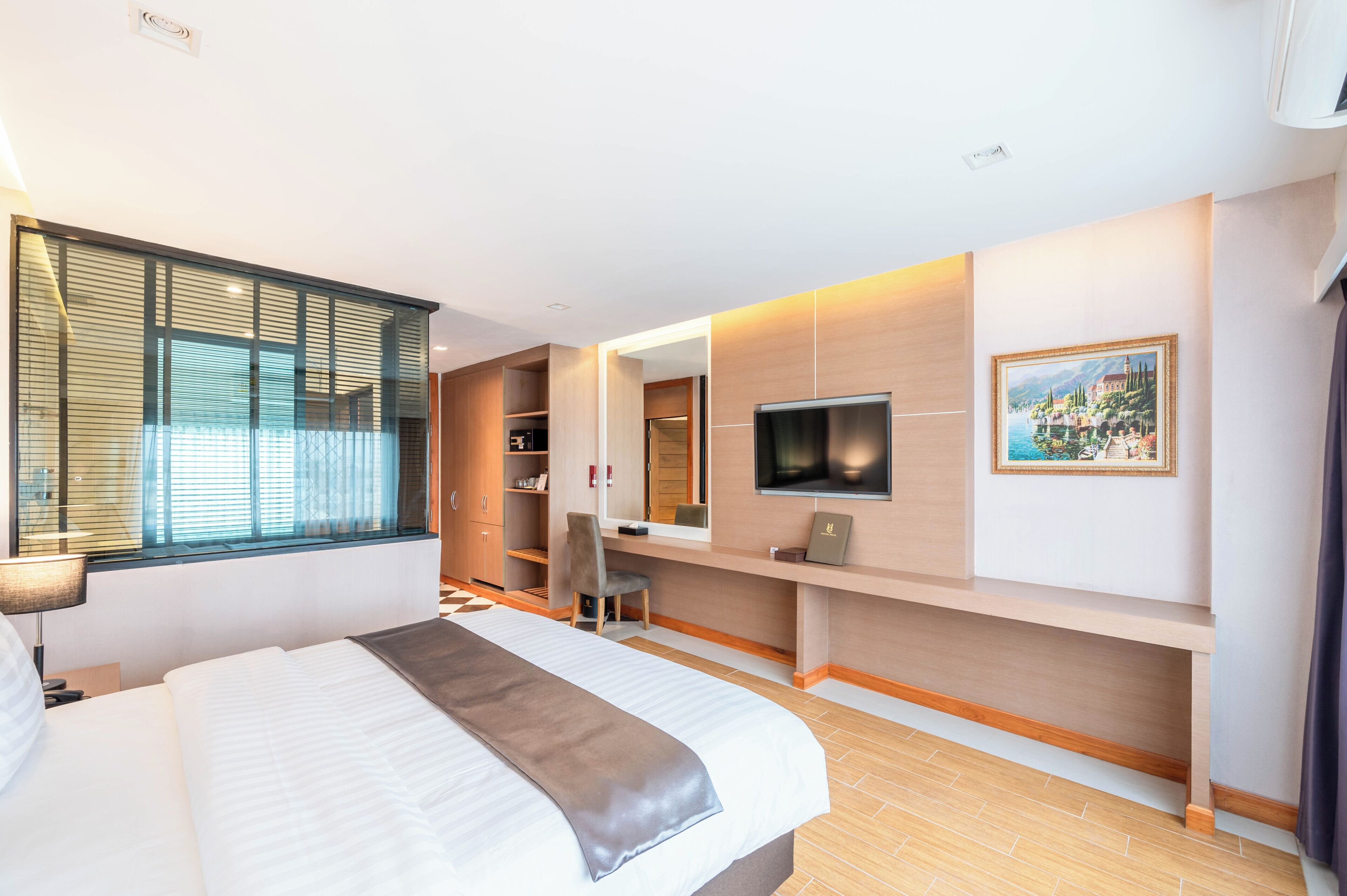 Ein modernes Hotelzimmer mit einem großen Bett, einem Schreibtisch, einem Fernseher und einem Bild an der Wand.