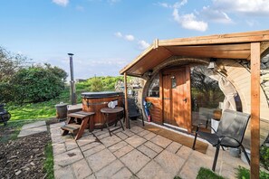 A wooden cabin with a stone patio, a hot tub, and a wooden deck. - Luxury Pod-Sleeps 2-Hot Tub-Pets-Garden (Sheerness)