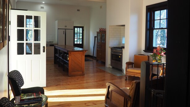 A spacious kitchen with a central island, wooden flooring, and a view of the outdoors through a window. - BALMORAL LODGE  - EXCLUSIVE COUNTRY ESCAPE (Cockatoo Valley)