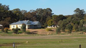 A two-story house with a blue roof, surrounded by a grassy field and trees. - BALMORAL LODGE  - EXCLUSIVE COUNTRY ESCAPE (Cockatoo Valley)