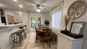 A dining area with a round table and chairs, a white cabinet with a decorative tree, and a ceiling fan. - Light & airy home w/private hot tub on golf course (Quinton)