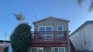 A two-story house with a balcony, a white picket fence, and a number 5022 on the front.