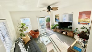 A living room with a sofa, a TV, and a ceiling fan.