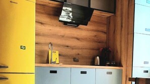 Una cucina moderna con mobili grigi e gialli, un piano di lavoro in legno e un frigorifero giallo.