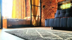 Una stanza con un muro in mattoni, un divano, un tappeto e un letto.