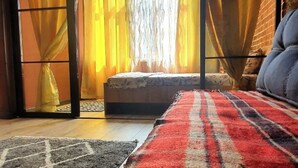 Una stanza con un letto, una finestra con tende e un tappeto decorato.