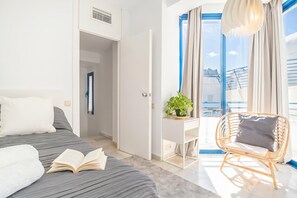 Ein modernes Schlafzimmer mit einem Bett, einer Leseecke mit Stuhl und Blick ins Freie.
