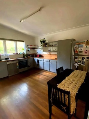 Enjoy meals in this kitchen with a central island, dining table, and refrigerator, offering a view of the surrounding greenery.