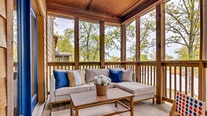 A covered porch with a wooden bench, a cushioned sofa, and a coffee table. - ONE Minute from Silver Dollar City! INDOOR Pool! (Branson)