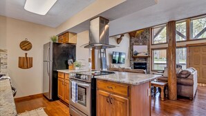 A kitchen with a central island, stainless steel appliances, wooden cabinets, and a stone accent wall. - ONE Minute from Silver Dollar City! INDOOR Pool! (Branson)