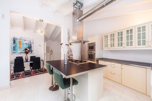 Uma cozinha moderna com uma ilha central, eletrodomésticos de aço inoxidável e armários em tons claros.