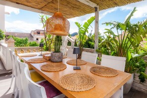 A wooden table with woven placemats, white chairs, a hanging lantern, and potted plants. - Finca Casa Varna with Mountain View, Pool, Terrace & Garden; Parking Available (Capdepera)