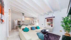En moderne stue med sofa, sofabord og udsigt til køkkenet.