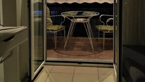 A balcony with a glass door, a small table, and two chairs. - Cozy Studio close to seaside and city center (Palaio Faliro)