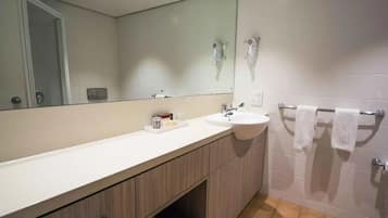 A bathroom with a white sink, a mirror, and a towel rack.