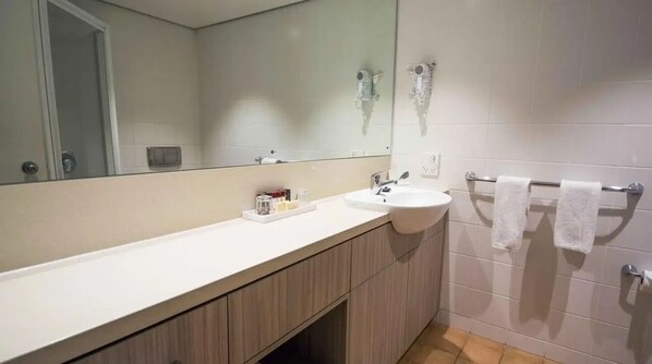 Une salle de bain avec un lavabo blanc, un miroir et un porte-serviettes.