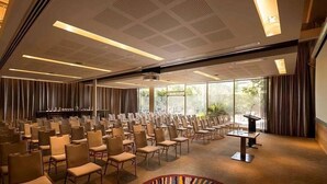 Un salón de conferencias con hileras de sillas, un atril y un amplio ventanal.