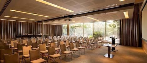 A conference room with rows of chairs, a podium, and a large window.