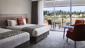 Habitación de hotel con dos camas, un sofá, una mesa de comedor y vistas al exterior.
