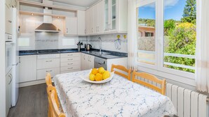 Une cuisine avec des meubles blancs, un plan de travail noir et une fenêtre donnant sur un paysage verdoyant.