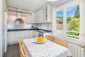 A kitchen with white cabinets, a black countertop, and a window with a view of greenery.