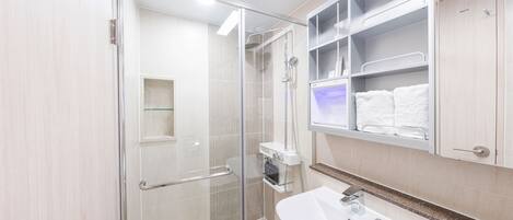 Un baño moderno con cabina de ducha de vidrio, un lavabo blanco y armarios empotrados.