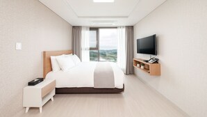 Habitación de hotel moderna con una cama grande, un televisor montado en la pared, una mesita de noche y vistas al exterior.