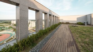 Un edificio moderno con un largo pasillo y vistas a un campo deportivo.