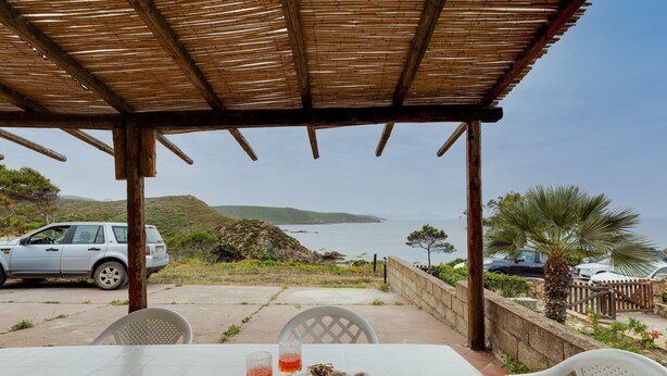 A table with a view of the sea, a parked car, and a palm tree. - Holiday Apartment "La Vista di Mondo" on the Beach with Sea View, Terrace & Garden (Torre dei Corsari Arbus)