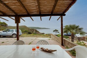 Une table avec vue sur la mer, une voiture garée et un palmier.