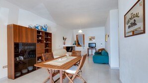 A dining area with a wooden table and chairs, a kitchen with cabinets, a sofa, and a television. - Holiday Apartment "La Vista di Mondo" on the Beach with Sea View, Terrace & Garden (Torre dei Corsari Arbus)